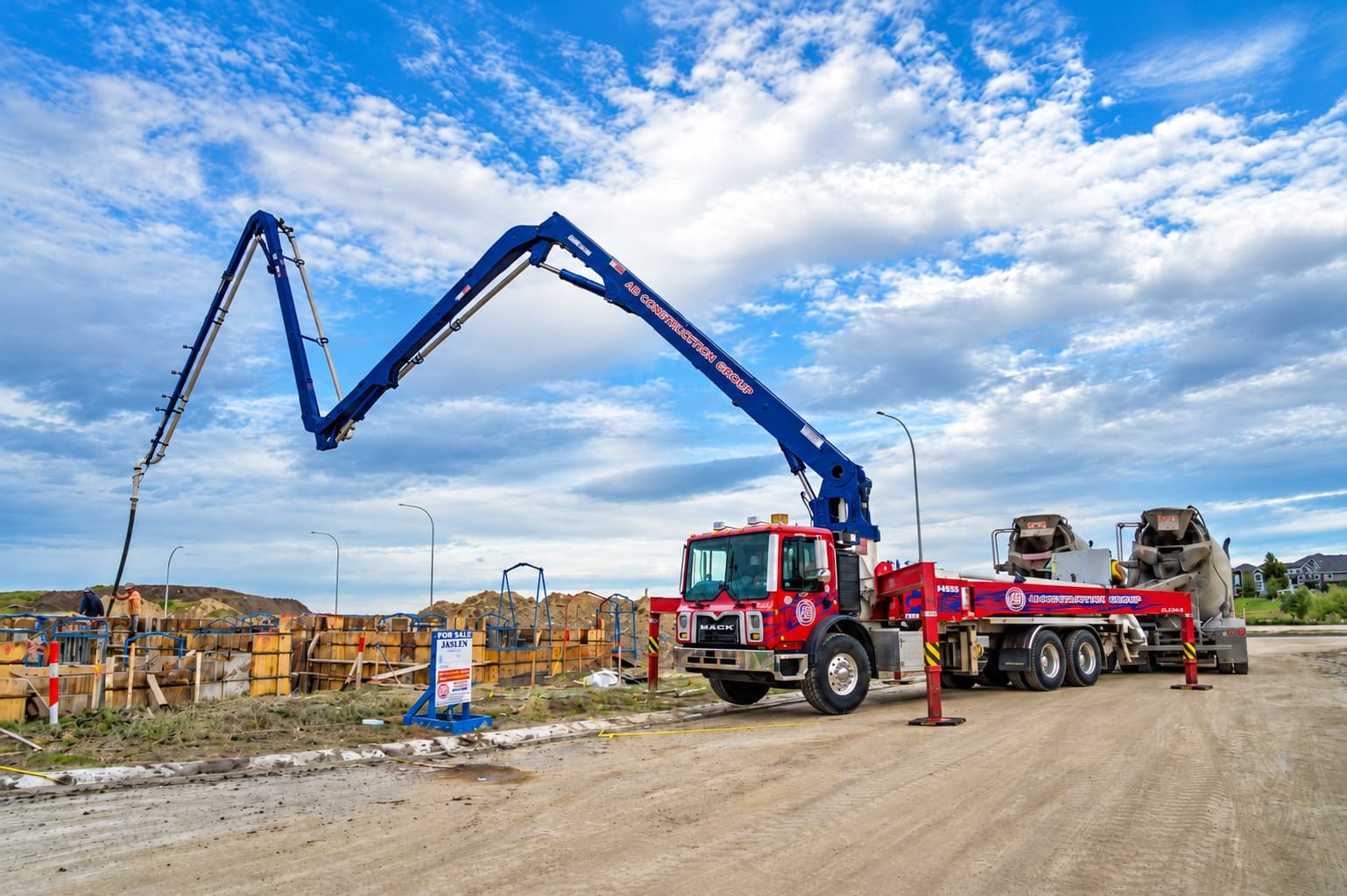AB Construction Group boom pump truck with its boom extended over foundation forms on an Alberta residential job site