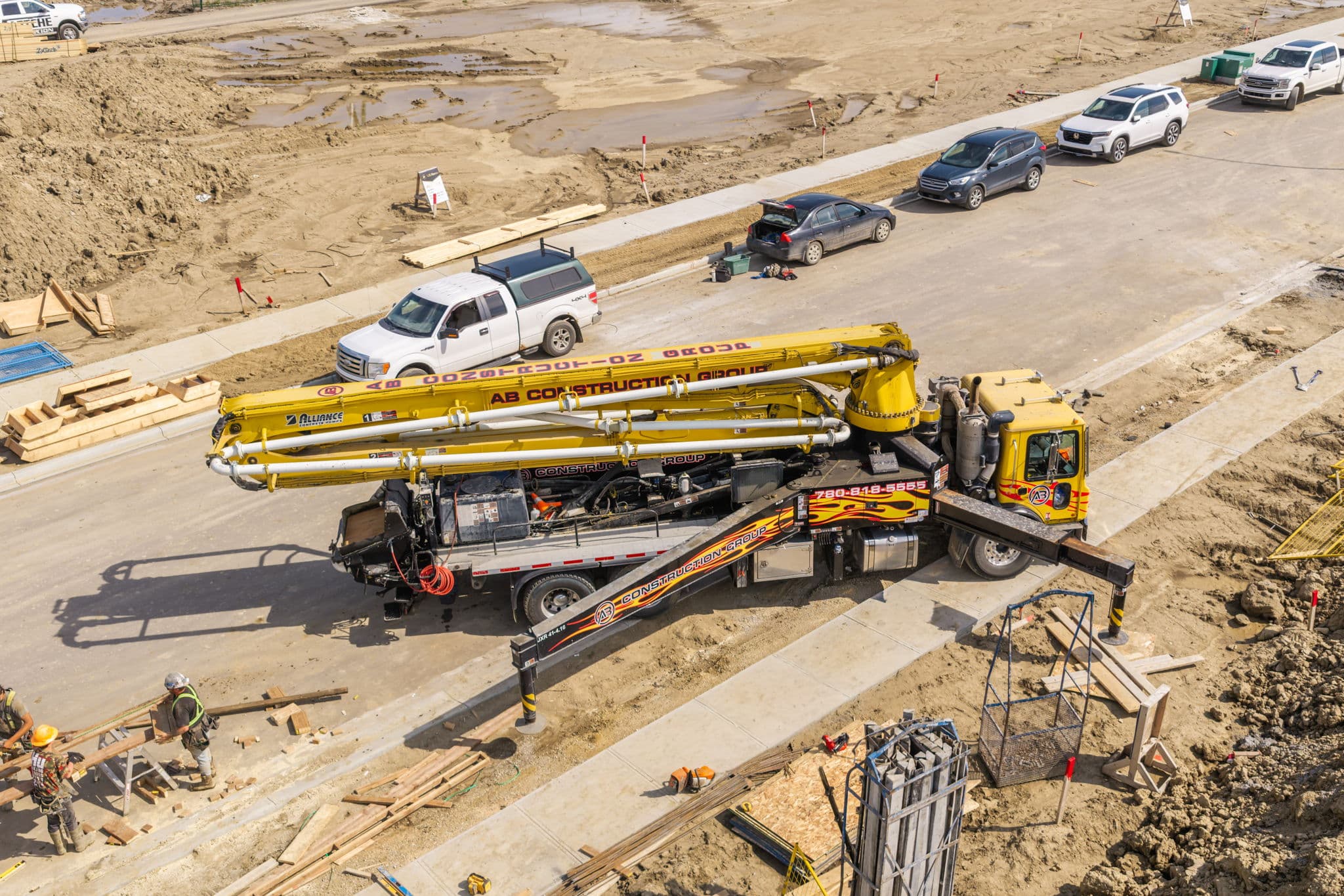 Overhead view of a boom pump truck with outriggers down on a new residential lot