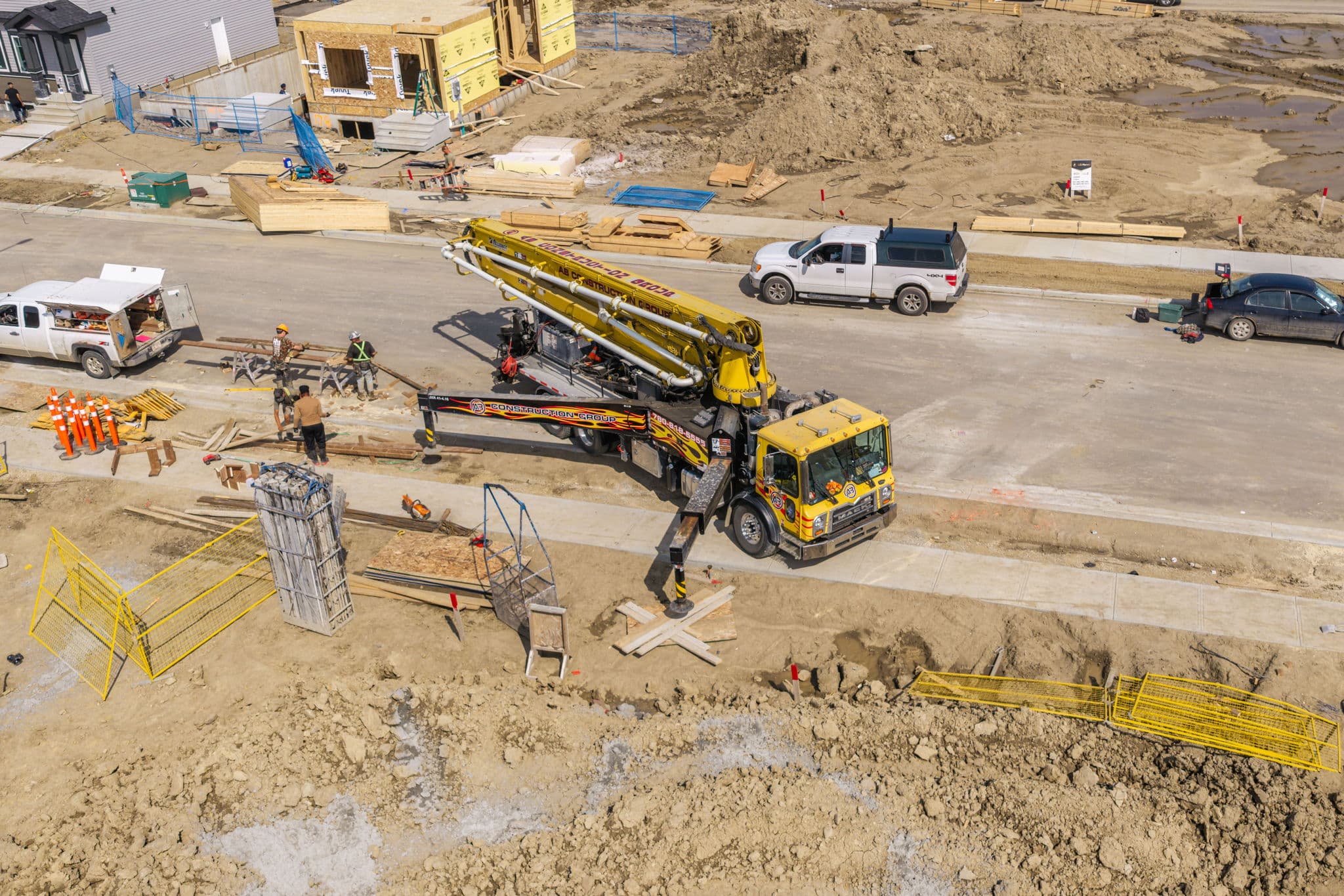 Boom pump truck staged on the street beside a home under construction, ready to place concrete
